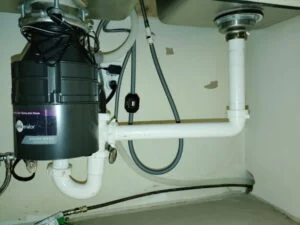 New kitchen sink drain and InSinkErator garbage disposal installed under a sink in Burleson, TX